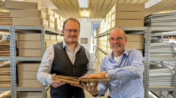 Das Bild zeigt den designierten Stadtarchivar Martin Münke und den scheidenden Stadtarchivar Christian Lopau im Ratzeburger Stadtarchiv, gemeinsam eine Archivale haltend.